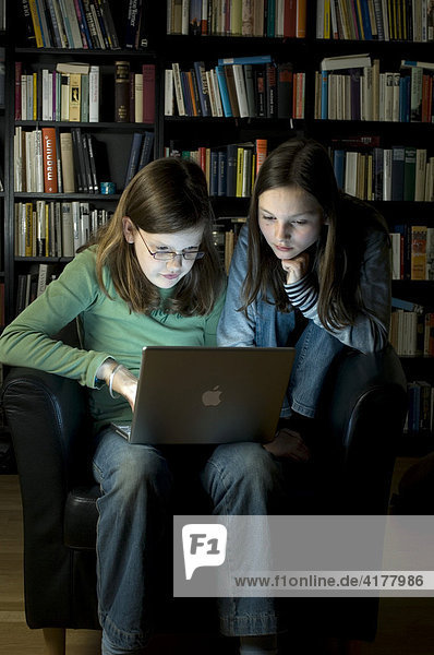 10jährige Mädchen an Computer vor Bücherwand