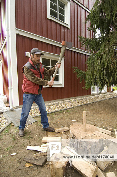 Mann beim Holz hacken vor Niedrigenergiehaus  Kleinmachnow  Brandenburg  Deutschland