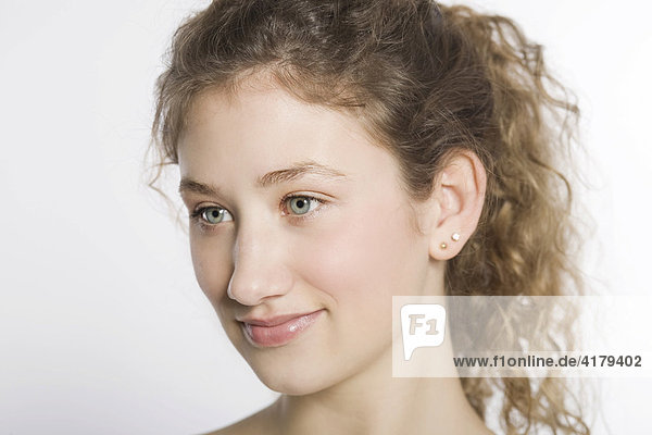 Lachende junge Frau mit gelockten Haaren im Halbprofil vor weißem Hintergrund