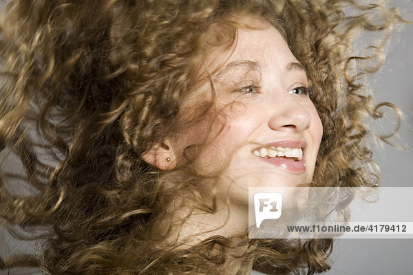 Junge Frau wirft ihre langen lockigen Haare hoch