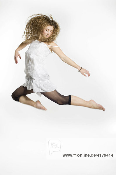 Junge Frau springt vor weißem Hintergrund