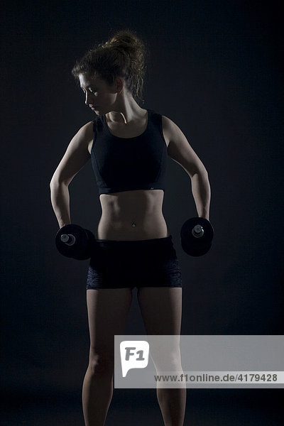 Young woman working out with dumbbells