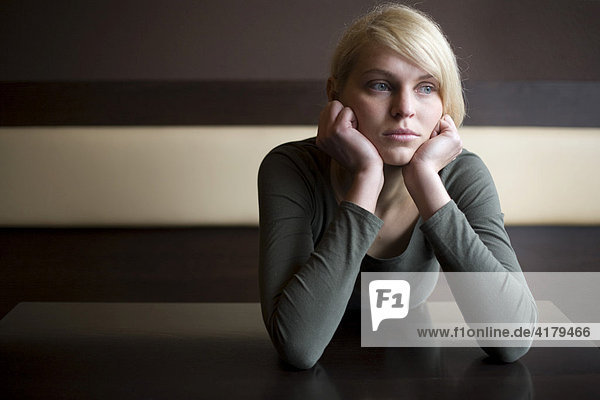 Blonde woman looking sad sitting at a table in a bar