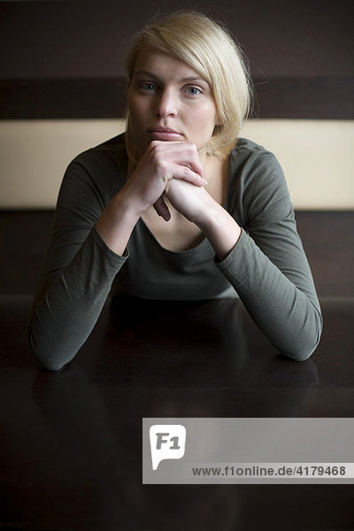 Blonde woman looking sad sitting at a table in a bar