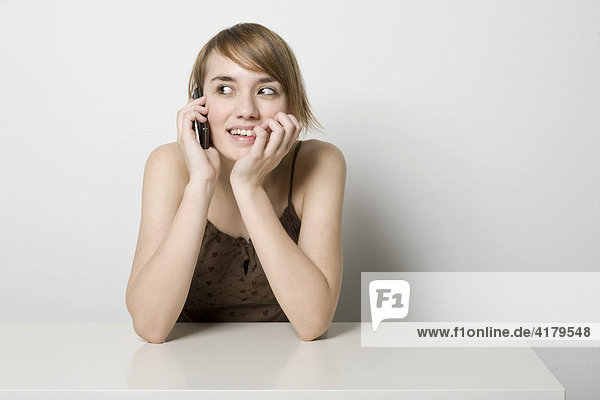 Young woman sitting at a table making a phone call
