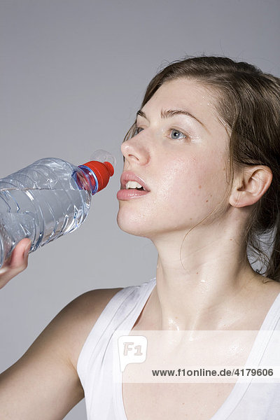 Young woman drinking from a bottle of water during workout
