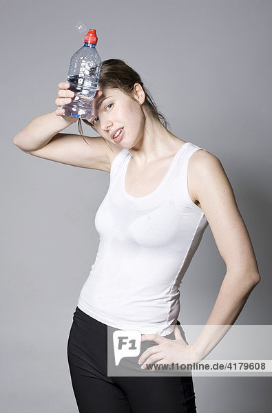 Erschöpfte junge Frau nach dem Fitnesstraining mit Wasserflasche in der Hand