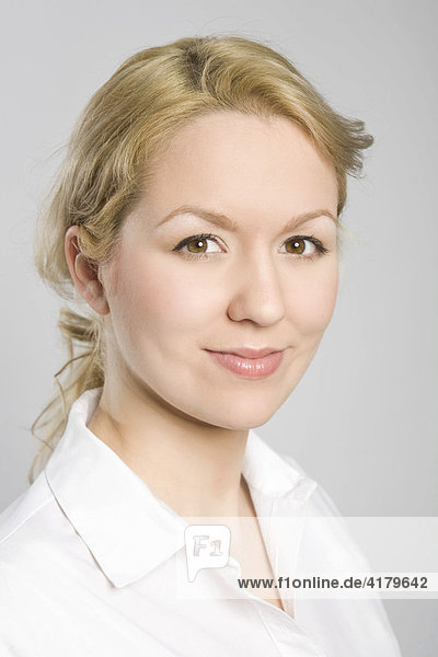 Portrait einer jungen blonden Frau in weißer Bluse  mit freundlichem Blick