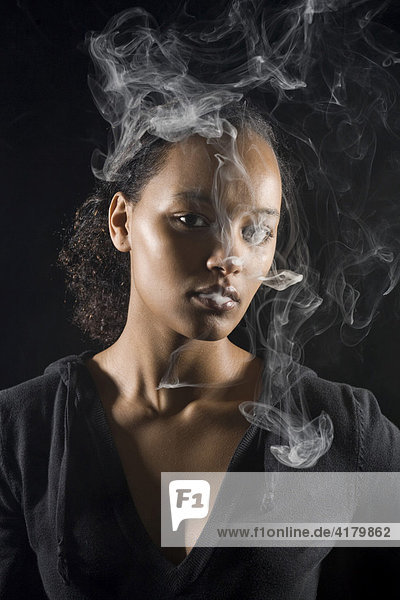 Junge dunkelhäutige Frau raucht eine Zigarette  Zigarettenqualm
