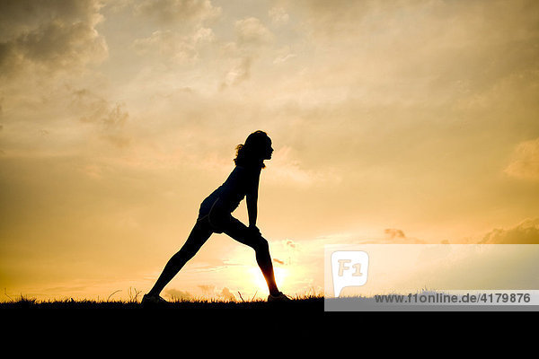 Silhouette of a woman stretching at sunset