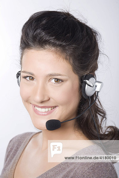Young woman with dark hair smiling while phoning on a headseat