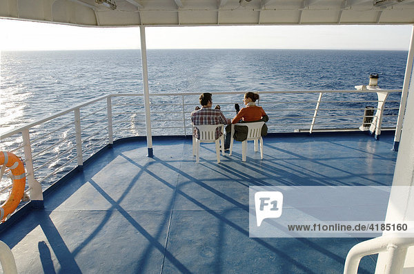 Seereise ein Mann und eine Frau  ein Paar  sitzen nebeneinander auf einem Schiffsdeck und blicken gemeinsam auf das Wasser  Mittelmeer  Griechenland.