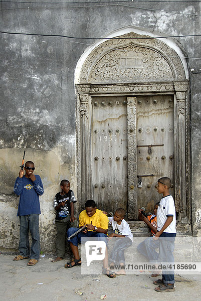Straßenszene  Kinder vor alter Tür in Stone Town  Sansibar  Tansania  Afrika