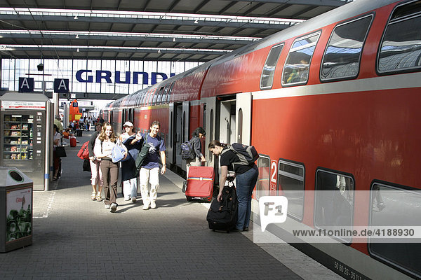 Menschen gehen auf dem Muenchner Hauptbahnhof an einem Zug entlang.