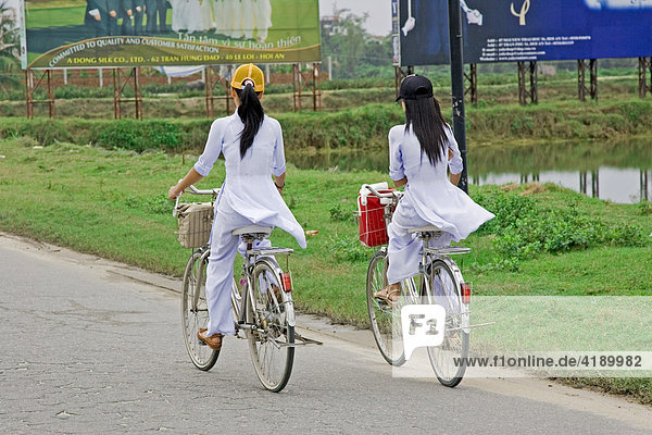 Students in the traditional ao dai dress on the way to school Vietnam