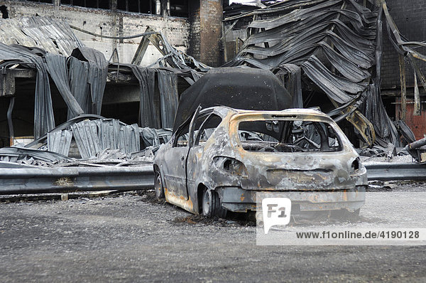 Ausgebranntes Fahrzeug vor Fabrikhalle stehend