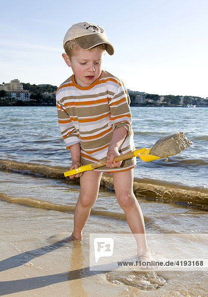Four-year-old boy with a spade on the beach of Santa Ponca  Majorca  Balearic Islands  Spain