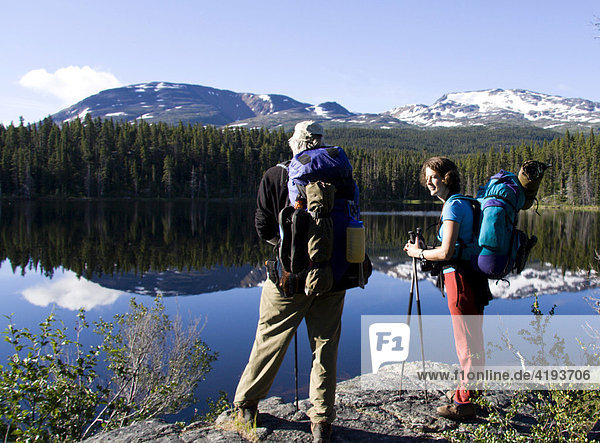 Hikers enjoying a view of glassy Dan Johnson Lake  Chilkoot Trail  British Columbia  Canada