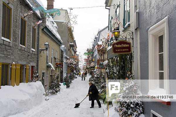 Woman shoveling snow in an alley in the historic centre of Québec City in winter  Québec  Canada