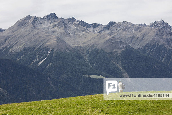 Panoramic view of lone person before a mountain landscape  Scuol  Lower Engadin  Switzerland  Europe