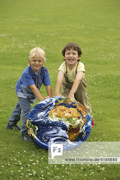 Children rolling a globe over a meadow