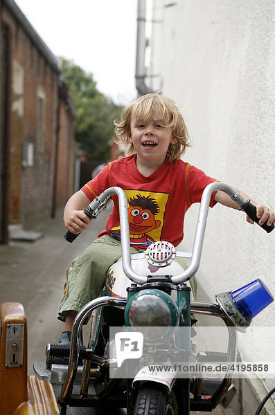 Porträt  dreijähriger Junge auf einem Spielgeräte-Motorrad