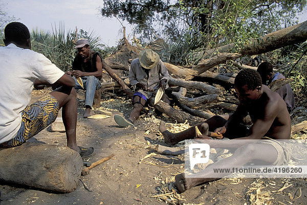 Touristenfuehrer im Okovango Delta beim Schnitzen von Souveniren aus Holz Botswana