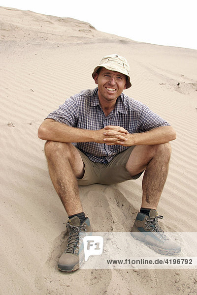 Mann sitzt im Sand