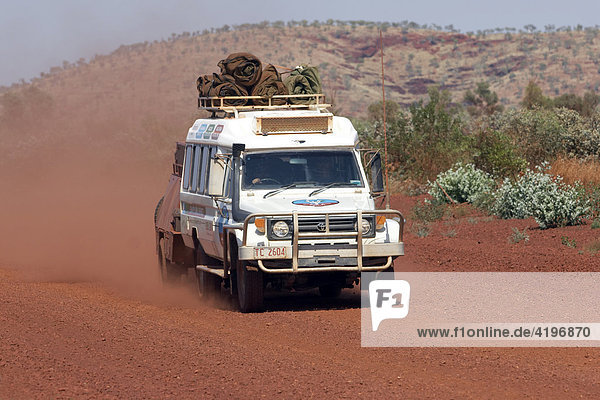 Fahrender Toyota Landcruiser FJ 75 Arkana Safari Fahrzeug mit Anhaenger auf roter Strasse in Karijini National Park Pilbara Region Westaustralien WA