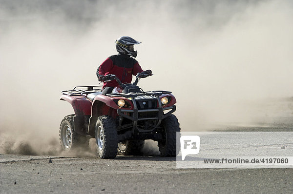 Quad drives on dusty piste