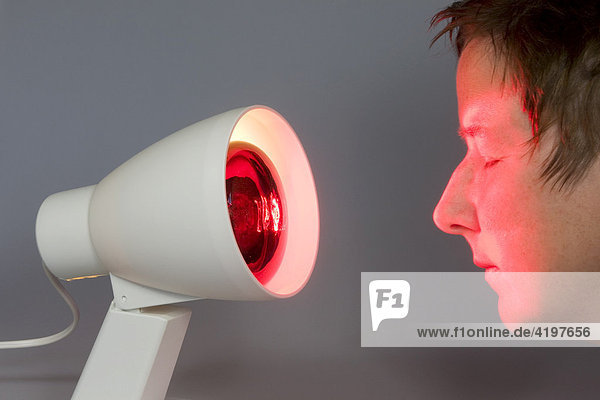 Rotlichtlampe  Infrarotlampe strahlt einer Frau ins Gesicht
