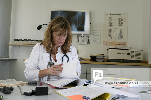 Woman doctor of a rehabilitation clinic reading results and detection reports
