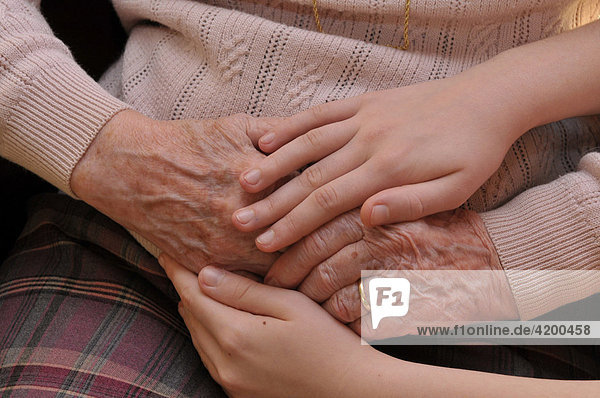 Kind hält Hand von Seniorin