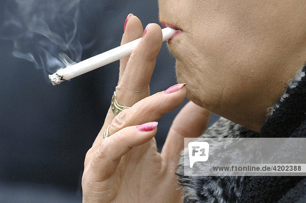 Rauchen - ältere Frau raucht eine Zigarette.