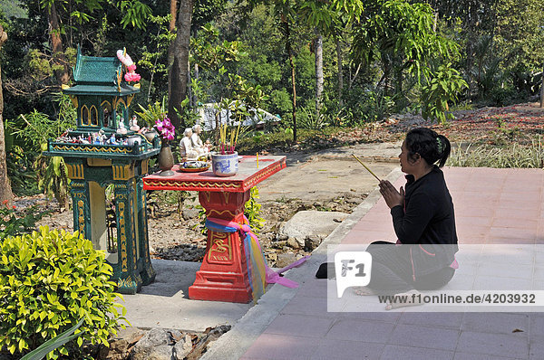 Woman praying on front of a spirit house (san phra phum)  Kho Chang  Thailand  Southeast Asia  Asia