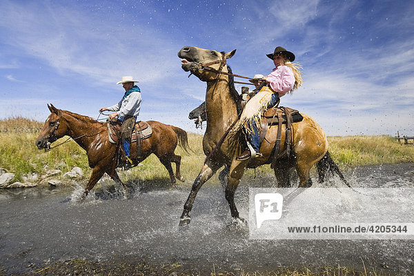 Cowgirl und Cowboy reiten durch Bach  Oregon  USA