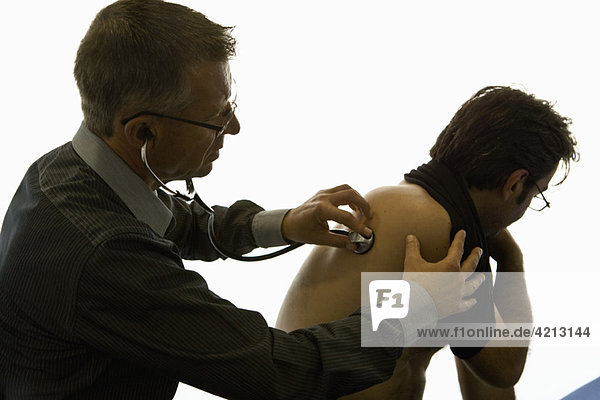 Arzt hört mit Stethoskop auf den Rücken des Patienten