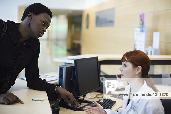 Female patient explaining problem to medical receptionist