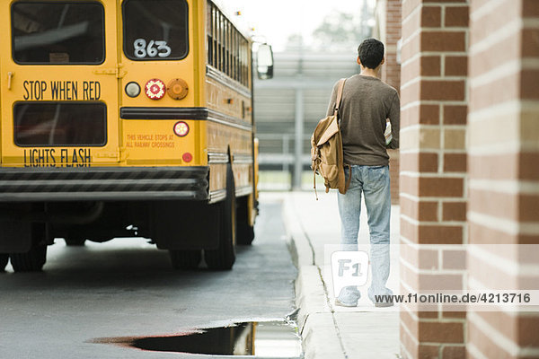 Gymnasiast wartet vor der Schule auf den Bus