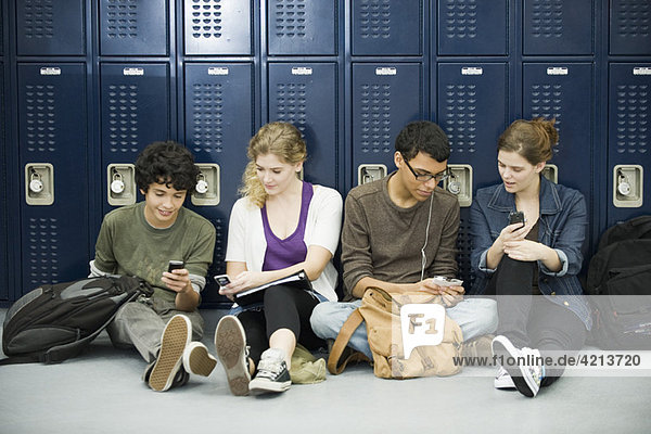 High school students hanging out  sitting on floor by lockers