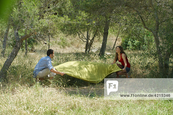 Smiling couple laying out picnic blanket