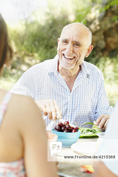 Lächelnder älterer Mann am Picknicktisch