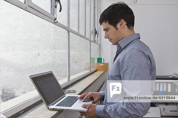 Mann arbeitet an seinem Laptop
