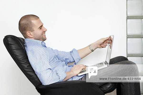 Mann sitzend mit Laptop im Knie