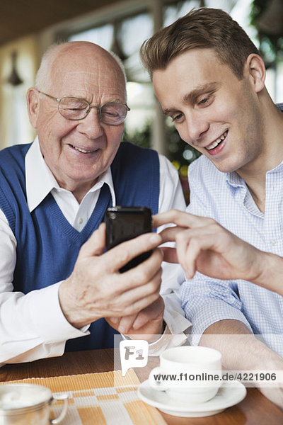 Elderly and young man using mobile phone