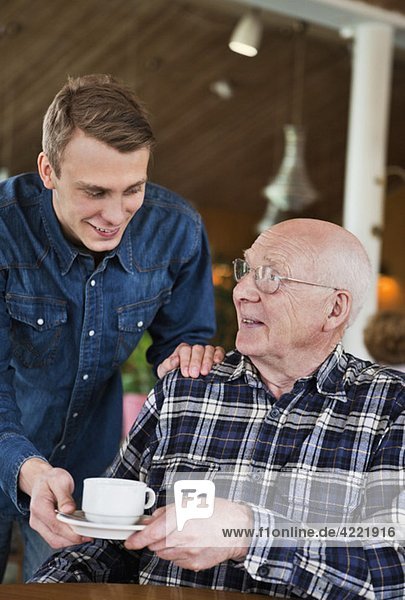 Grandchild serving coffee to grandfather