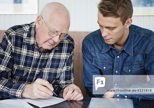 Man helping senior to fill in a form