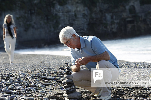 Senior stapelt Steine am Strand  Italien  Sori