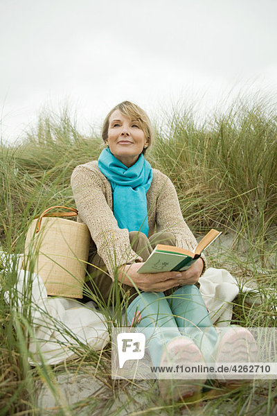 Frau an der Küste mit einem Buch