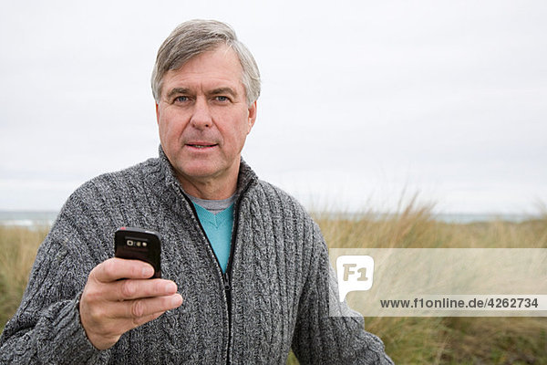 Mann an der Küste mit Smartphone